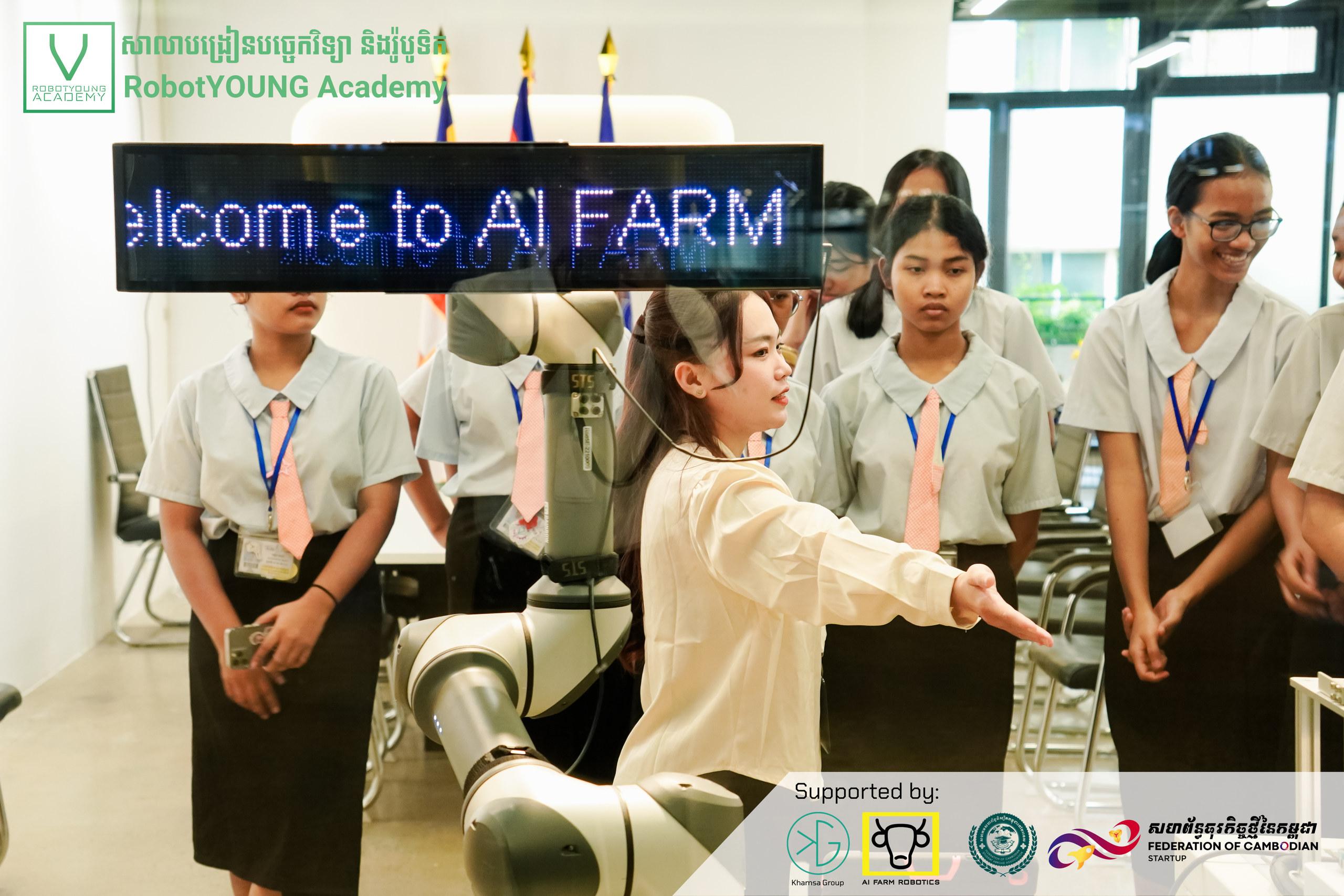 A guide demonstrating a robotic arm to visitors beside a Welcome to AI FARM display