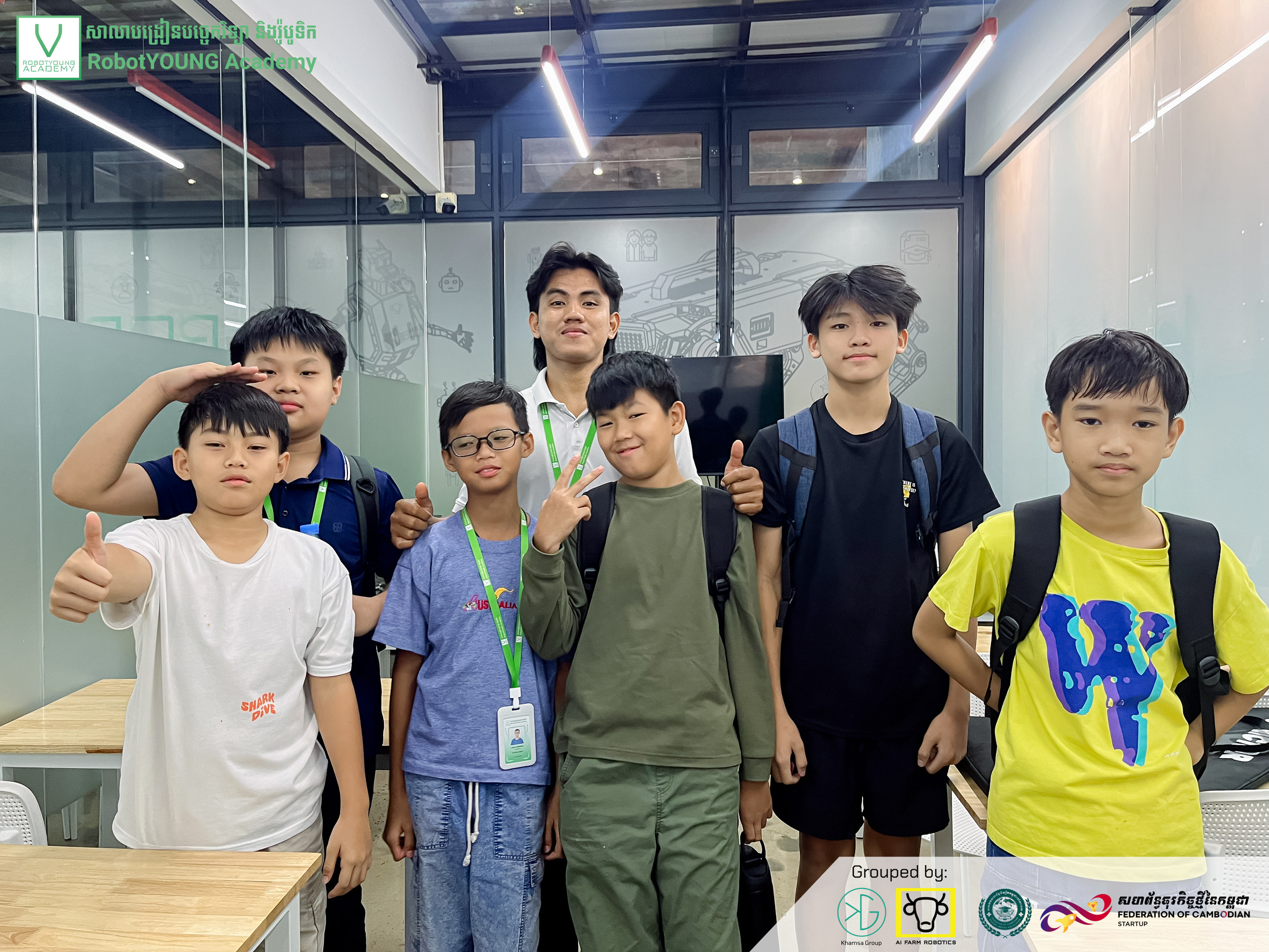 Students and an adult posing together in a robotics classroom